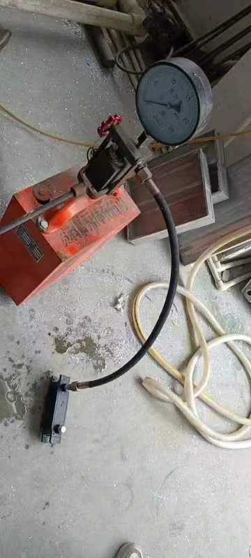 Oil cooler connected by a hose to a pressure-test pump and analog pressure gauge