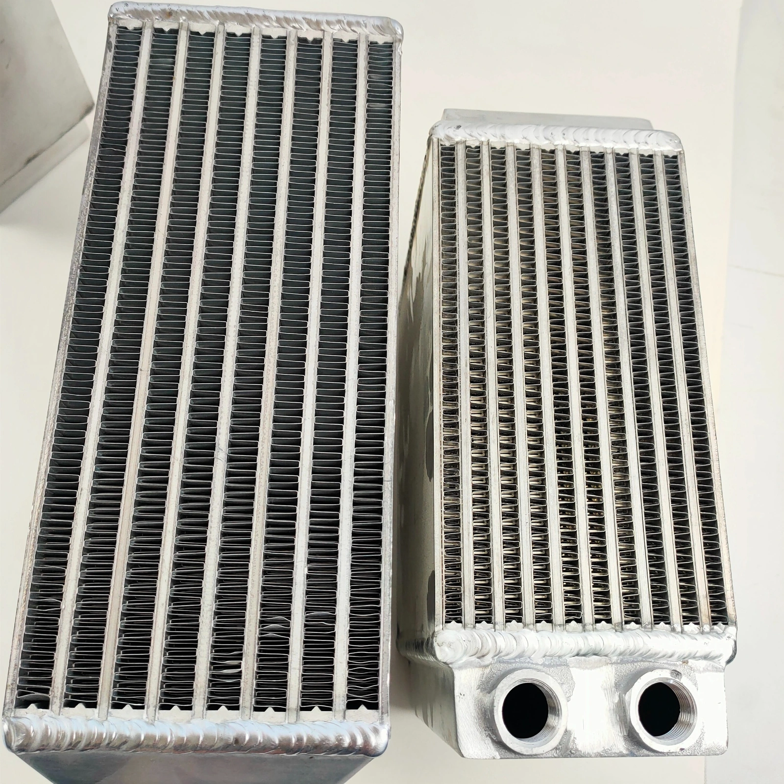 Two water-to-air intercooler cores side by side: the left core has fewer water passages and taller air-channel fins; the right core has more water passages